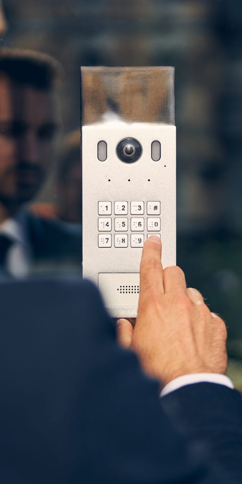 Brunette male in official clothes staing outside while pressing key for door to open